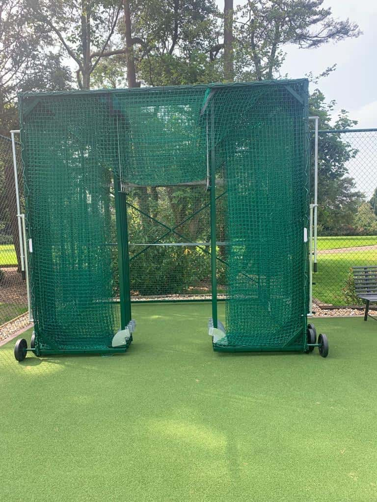 This is a photo of a tennis court with the net posts which have been folded up in the corner of the court.