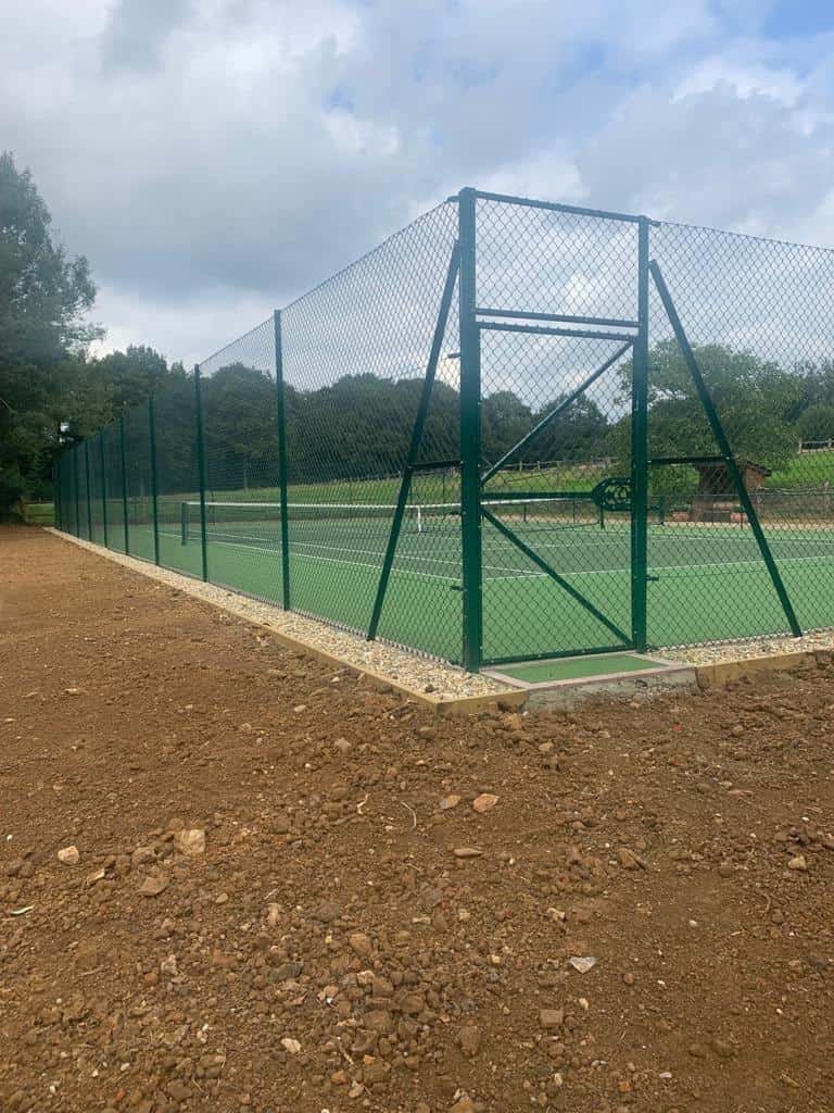 This is a photo of a newly installed tennis court. The court has also had a new side fencing with tapered drop. There is also a viewing area to the side of the middle of the court by the service line.